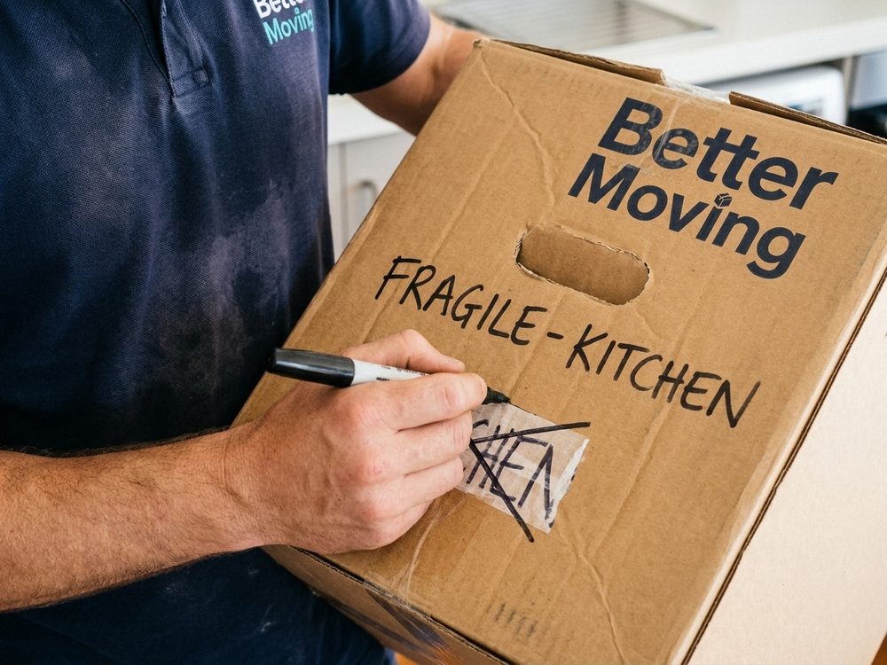 Glassware being wrapped individually in packing paper and placed into a carton.